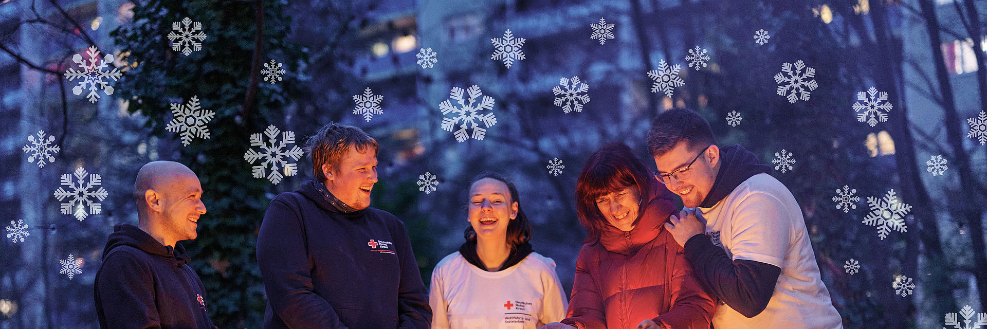 Header, helfende Ehrenamtliche wärmen sich die Hände am Feuer